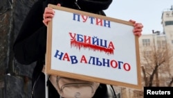 Жінка тримає плакат із написом «Путін – убивця Навального» під час мітингу пам’яті російського опозиціонера Олексія Навального у Москві, Росія, 17 лютого 2024 року