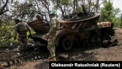Українські військовослужбовці оглядають знищену російську БМП-2 у звільненому від армії РФ селі Сторожеве на Донеччині, 14 червня 2023 року