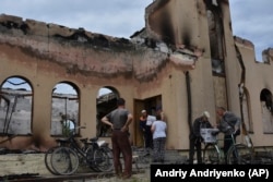 Місцеві жителі отримують гуманітарну допомогу від волонтерів перед молитовним будинком євангельських християн-баптистів, який зруйнував удар Росії в Оріхові, Запорізька область, Україна