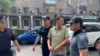 Улукбек Карыбек уулу милиция кызматкерлеринин коштоосунда кетип баратат. 