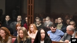 На задньому плані (за склом) ув’язнені українські громадяни в суді у російському Ростові-на-Дону, більшість із них – військовополонені, бійці полку «Азов». Росія, Ростов-на-Дону, 14 червня 2023 року 