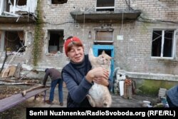 Жительница Авдеевки со спасённой кошкой возле своего многоквартирного дома, который серьёзно пострадал от постоянных российских военных ударов по городу в Донецкой области Украины (Сергей Нужненко, Украинская служба Азаттыка)