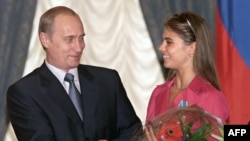 Владимир Путин вручает цветы Алине Кабаевой, звезде художественной гимнастики и победительнице Олимпийских игр, после награждения ее орденом Дружбы во время ежегодной церемонии награждения в Кремле. 8 июня 2001 года