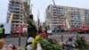 Люди несуть квіти, свічки та іграшки до будинку, зруйнованого російською ракетою, Дніпро, 16 січня 2023 року