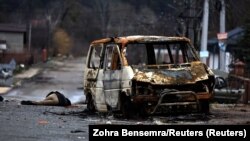 Тіло убитої російськими військовими цивільної людини та спалений автомобіль на вулиці Бучі. 2 квітня 2022 року