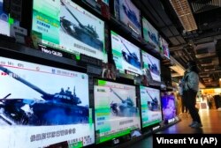 Женщина стоит перед экранами телевизоров, транслирующих новости о российских войсках, начавших наступление на Украину. Гонконг, 24 февраля 2022 года