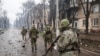 Російські військові ідуть зруйнованою вулицею Маріуполя. 13 квітня 2022 року 