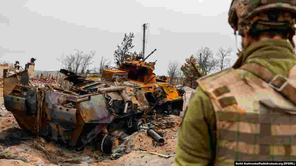 Український військовий оглядає знищений російський бронетранспортер БТР-82 у селі Тетерівське поблизу лінії фронту, 31 березня 2022 року