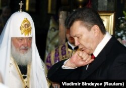 Києво-Печерська лавра. Віктор Янукович (праворуч) перед його інавгурацією на посаду президента України і глава Російської православної церкви (РПЦ) Кирило (Гундяєв). На фото Янукович цілує нібито «княжий перстень», який йому подарував Московський патріарх. Київ, 25 лютого 2010 року