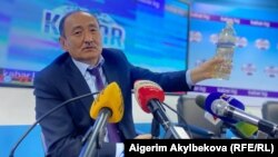 Министр здравоохранения Алымкадыр Бейшеналиев на пресс-конференции с бутылкой с отваром из аконита. 16 апреля 2021 года. 