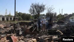 Місцеві жителі стоять на місці будівлі, зруйнованої російськими військовими у селі Ямпіль, Сумська область, Україна, 6 вересня 2024 року