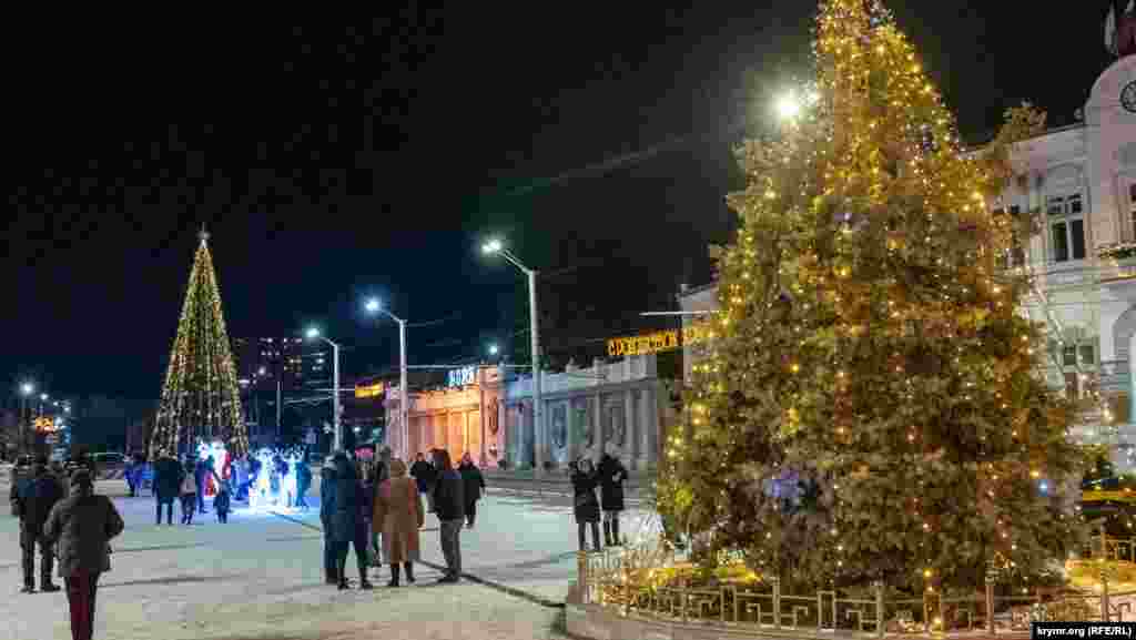 Евпатория. В этом году на Театральной площади установили искусственную главную городскую елку высотой 11 метров. Прежде такой роли удостаивалась живая, растущая, которую тоже украсили (справа).