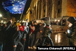 Протестувальники рухаються в бік спецпризначенців, прикриваючись імпровізованим щитом біля будівлі Парламенту