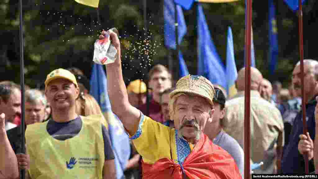 Чоловік сипле гречку в бік Верховної Ради під час мітингу з вимогою до депутатів зняти з себе недоторканність та змінити виборчу систему. Київ, 6 вересня 2018 року. БІЛЬШЕ ФОТОГРАФІЙ ПРО ЦЕ