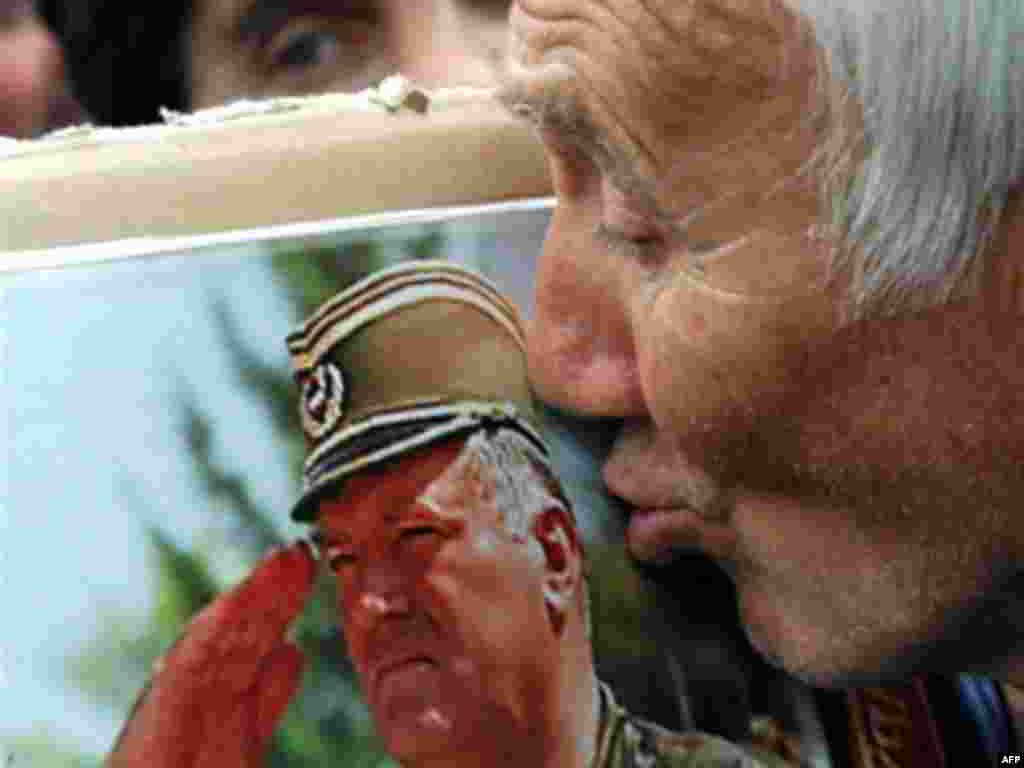 Младичтин колдоочусу анын сүрөтүн өбүүдө. - Сербиянын ордосу Белград шаарында Ратко Младичтин тарапкери болгон аял Младичти жактаган демонстрация маалында анын сүрөтүн өбүүдө. 2008-жылдын 6-майы.