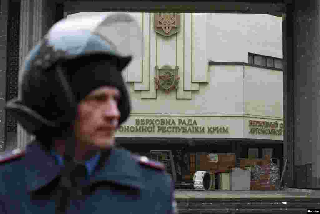 Співробітник МВС стоїть біля будівлі кримського парламенту в Сімферополі, який захопили невідомі озброєні люди