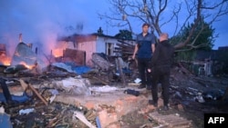 Місцеві жителі оглядають залишки свого зруйнованого будинку після атаки російського безпілотника в передмісті Харкова, 21 травня 2024 року. Фото ілюстративне