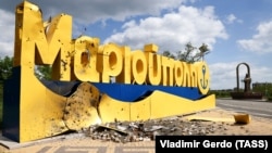 Ушкоджена обстрілом стела на в'їзді до міста Маріуполь з боку Бердянська та пам'ятник митрополиту Ігнатію Маріупольському (праворуч), 23 травня 2022 року