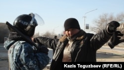 Сотрудник полиции проверяет мужчину в городе Жанаозен Мангистауской области, 19 декабря 2011 года.