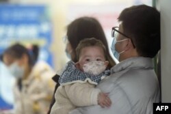 Ребенок в маске ждет вместе с членами семьи в педиатрическом отделении больницы в Ханчжоу, провинция Чжэцзян на востоке Китая, 6 января 2025 года. Фото AFP