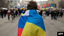 Учасник акції, яка пройшла за день до «референдуму» в Криму (визнаного більшістю країн світу незаконним), стоїть з прапорами України і Росії. Москва, 15 березня 2014 року