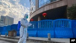 Співробітник у захисному одязі поблизу госпіталю в місті Ухань, Китай, лютий 2021 року