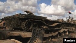 Каддафичил жоокердин жарактан чыккан танктын жанында жаткан бут кийими. Бенгази менен Аждабиян ортосундагы жол. 21-март