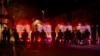 Polițiști înarmați în echipament antirevoltă stau de pază în timpul celei de-a doua nopți de revolte, în Ballymena. 10 iunie 2025.